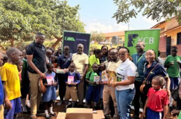 Some of the KCB staff pose for a photo with pupils from St.Jude Primary School as they hold some of the reading material donated by the bank