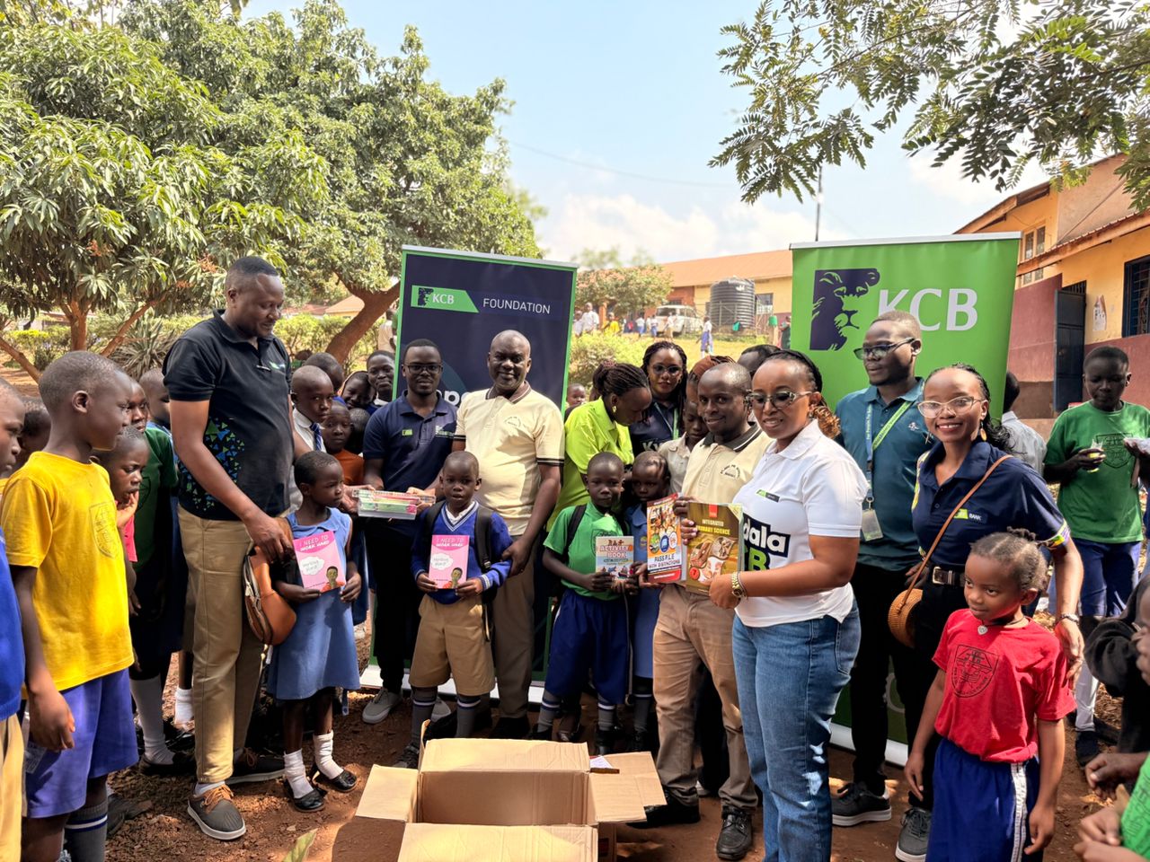 Some of the KCB staff pose for a photo with pupils from St.Jude Primary School as they hold some of the reading material donated by the bank Some of the KCB staff pose for a photo with pupils from St.Jude Primary School as they hold some of the reading material donated by the bank